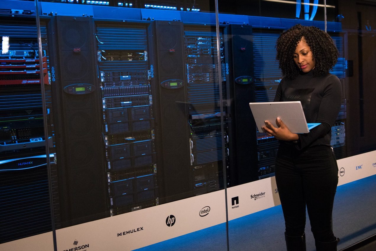 blog-servers2x woman looks at a computer while standing in front of servers