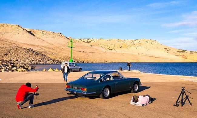 A photographer taking photographs of a classic car.